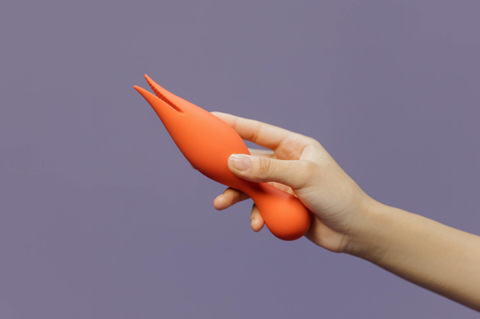 A hand holding a lemon-colored vibrator against a minimalist backdrop, representing gentle pleasure during healing
