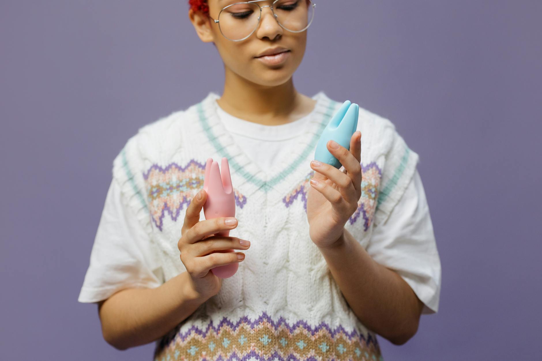 Woman holding colorful silicone vibrators in contemplation
