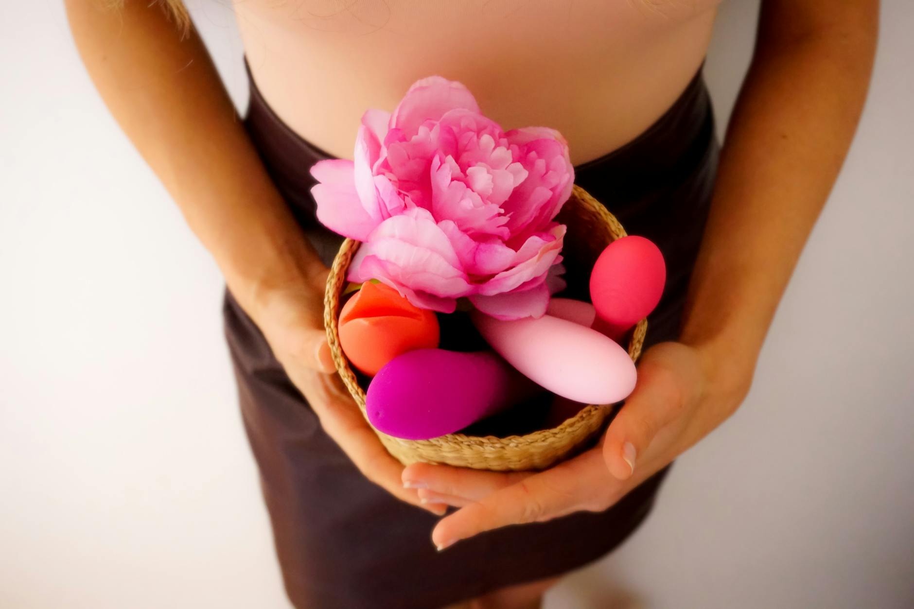 A basket containing colorful vibrators and flowers, representing gentle pleasure exploration.